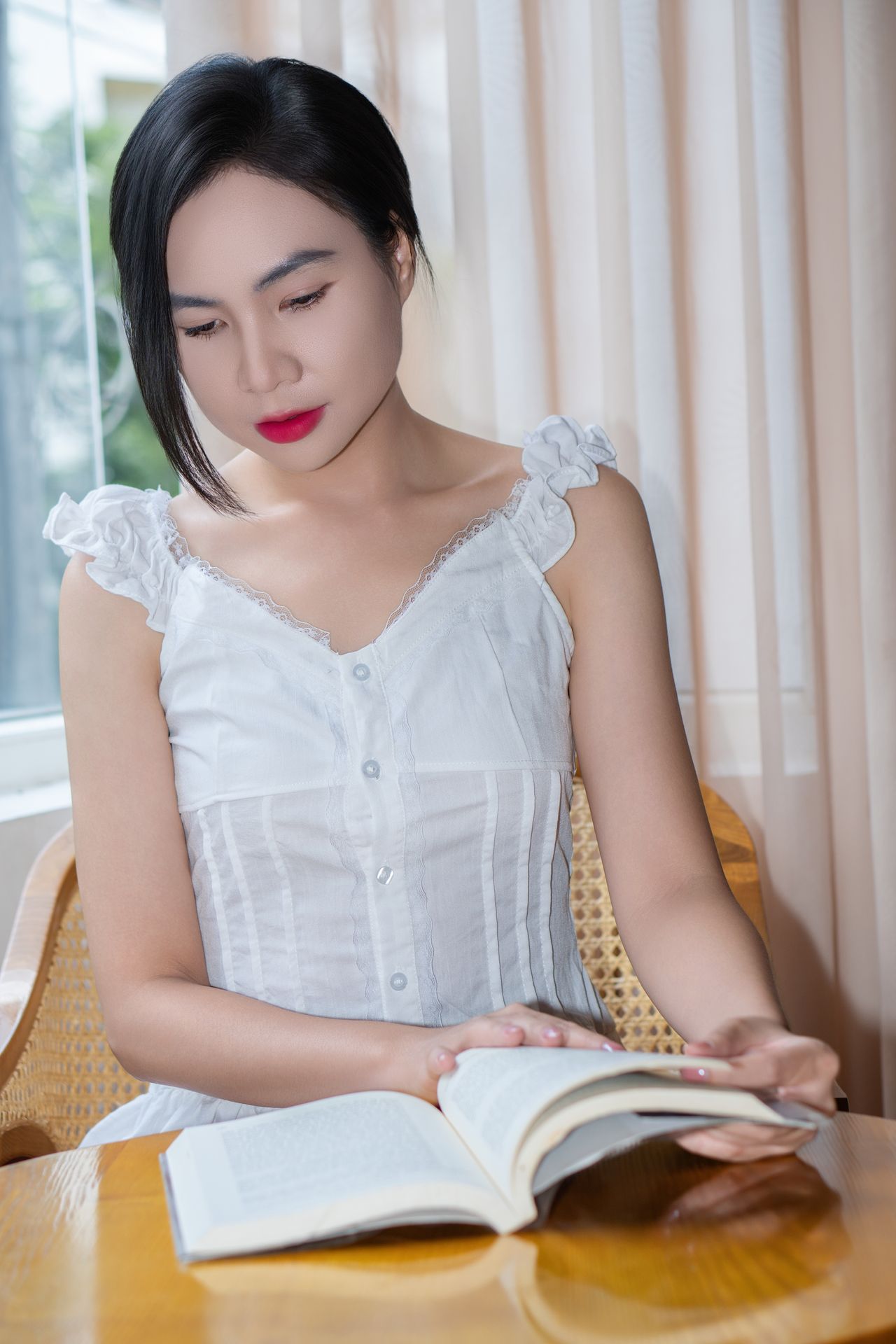 Young woman reading by window in soft light